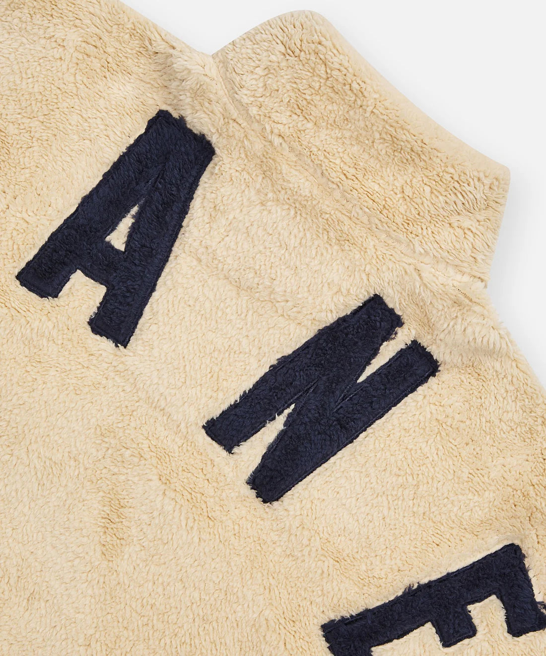 Paper Plane ecru sherpa half-zip pullover with faux sherpa letter appliqué, kangaroo pocket, and relaxed fit.