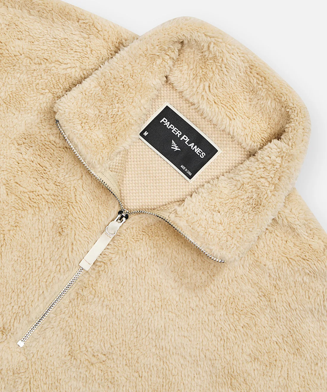 Paper Plane ecru sherpa half-zip pullover with faux sherpa letter appliqué, kangaroo pocket, and relaxed fit.