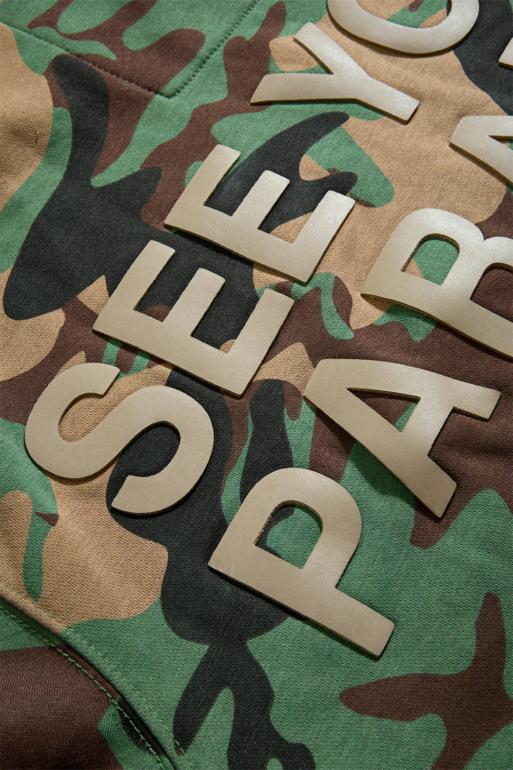 The SYIP Pullover Hoodie in Vintage Camo brings a sharp, technical look with everyday comfort. Designed in a classic hoodie silhouette, it features an all-over camo print and tonal high-density graphics on the chest and back. Made from combed cotton low-shrinkage fleece, this hoodie delivers softness, durability, and a crisp fit. Finished with ribbed cuffs, a ribbed waistband, and a front kangaroo pocket, it pairs perfectly with the matching SYIP Stacked Sweatpants in Vintage Camo.