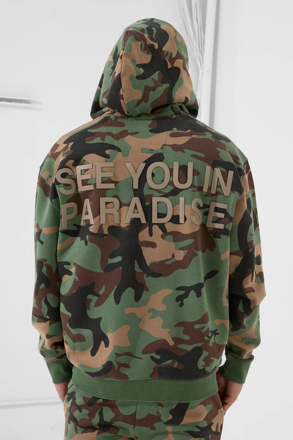 The SYIP Pullover Hoodie in Vintage Camo brings a sharp, technical look with everyday comfort. Designed in a classic hoodie silhouette, it features an all-over camo print and tonal high-density graphics on the chest and back. Made from combed cotton low-shrinkage fleece, this hoodie delivers softness, durability, and a crisp fit. Finished with ribbed cuffs, a ribbed waistband, and a front kangaroo pocket, it pairs perfectly with the matching SYIP Stacked Sweatpants in Vintage Camo.