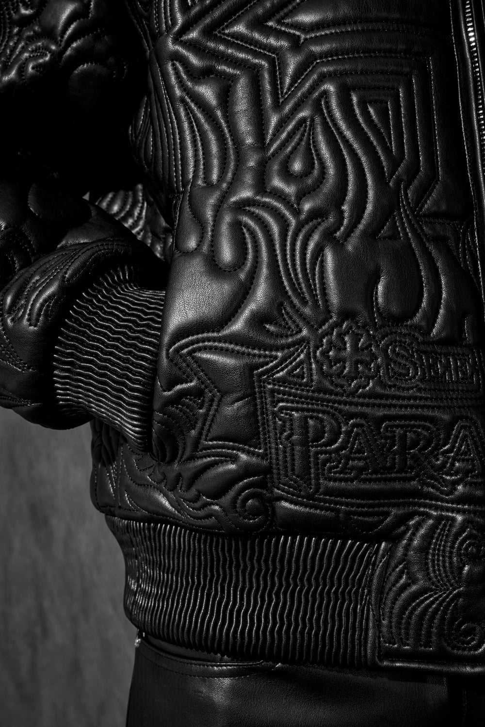 “Sinister Bomber Jacket – Charcoal: classic bomber silhouette, quilted embroidery, vegan leather accents, insulated channels, and branded zippers for style and warmth.”