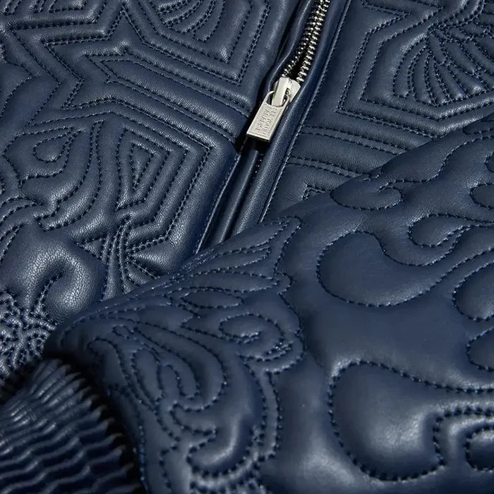 Navy kid’s bomber jacket with quilted embroidery, ribbed cuffs, vegan leather, and insulated interior.