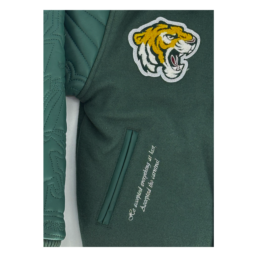 The SYIP Team Varsity Jacket in Dark Green delivers classic varsity style with premium detailing. Crafted with a wool body and vegan leather sleeves alongside a quilted satin lining, it offers both comfort and durability. Striped ribbed trims, chenille patches, and embroidered designs throughout give the jacket a standout, street-ready look. A snap button front closure ensures easy wear for everyday styling.