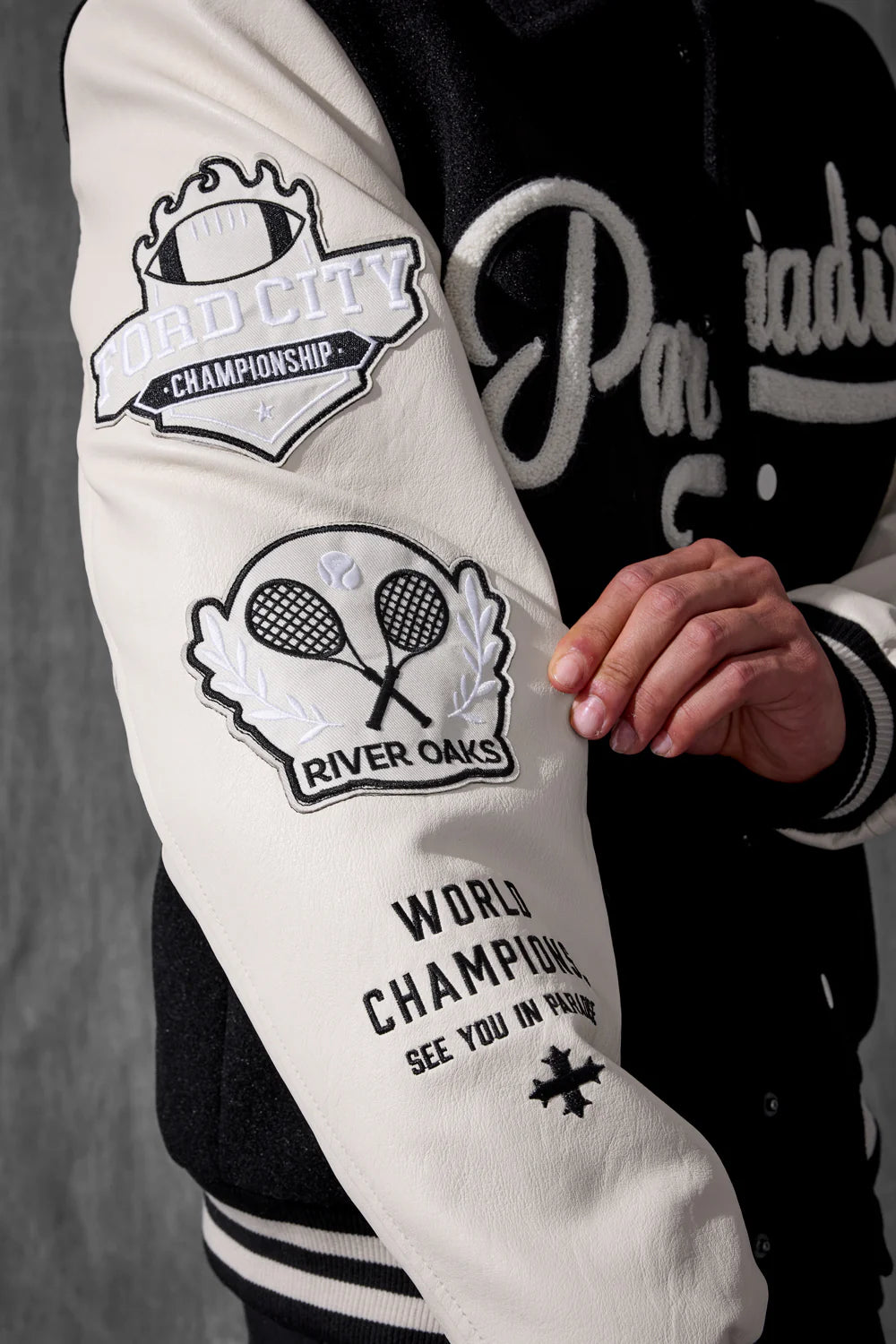 Close-up of a white varsity jacket with embroidered logos and text.