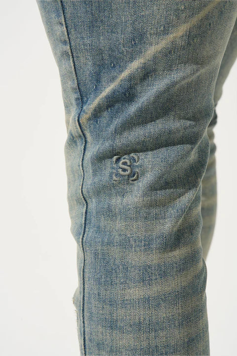SERENEDE® ATLAS vintage sea blue-concrete jeans with fitted construction, distressing on top thigh, whiskering fade, leather waistband patch, holographic hangtag, and branded hardware