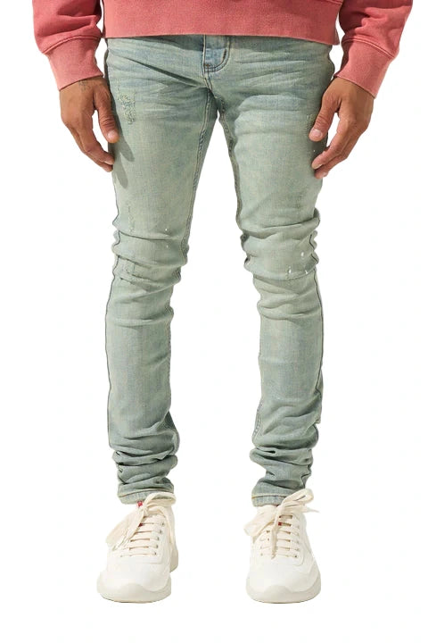 SERENEDE® AURA vintage earth blue jeans with white paint detailing on knee, fitted construction, fading and distressing, leather waistband patch, holographic hangtag, and branded hardware