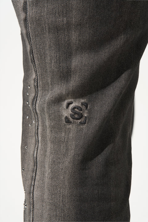 SERENEDE® COSMOS light grey jeans with black overspray, multi-sized gems, fitted construction, leather waistband patch, holographic hangtag, and branded hardware