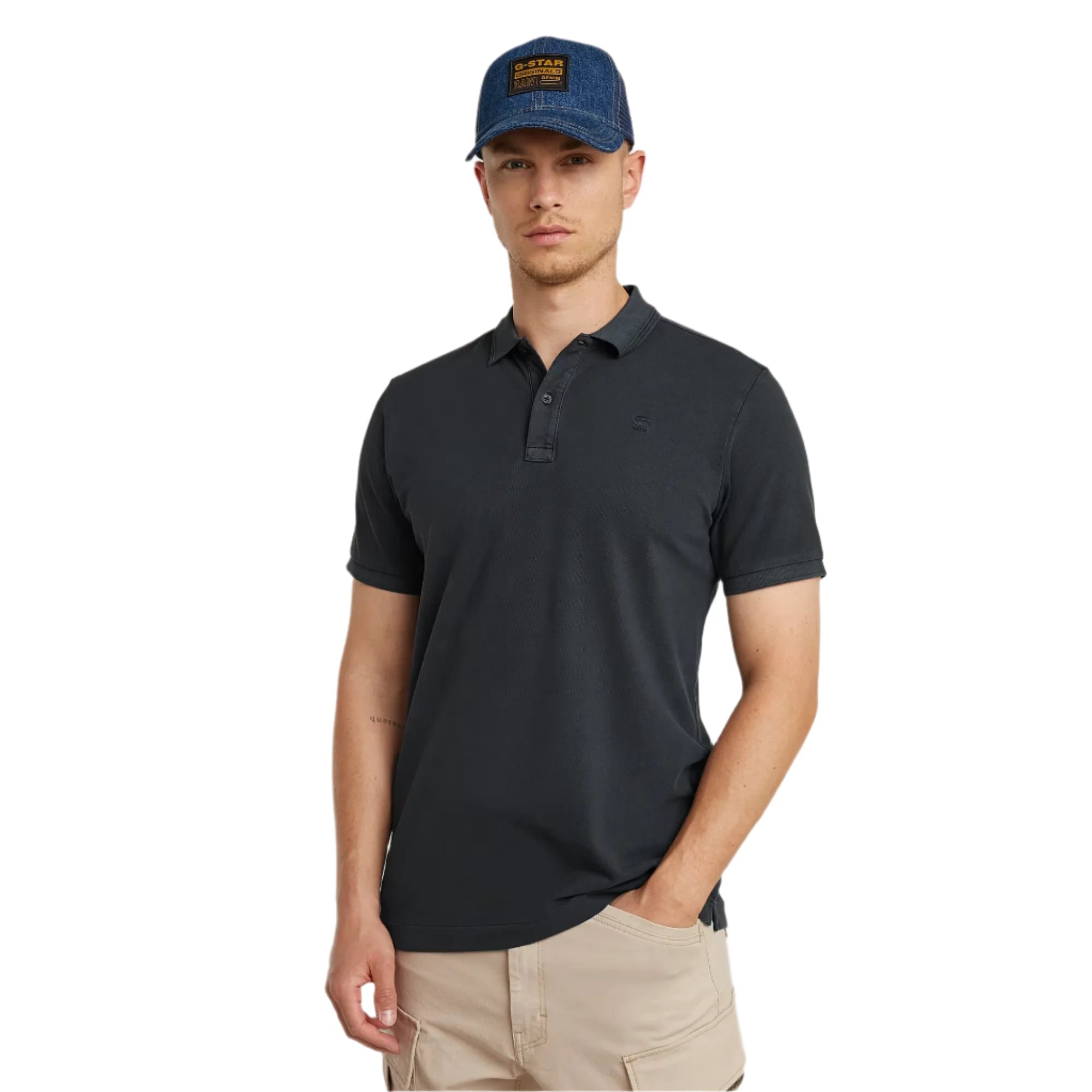 Man wearing a black polo shirt and blue cap against a plain background