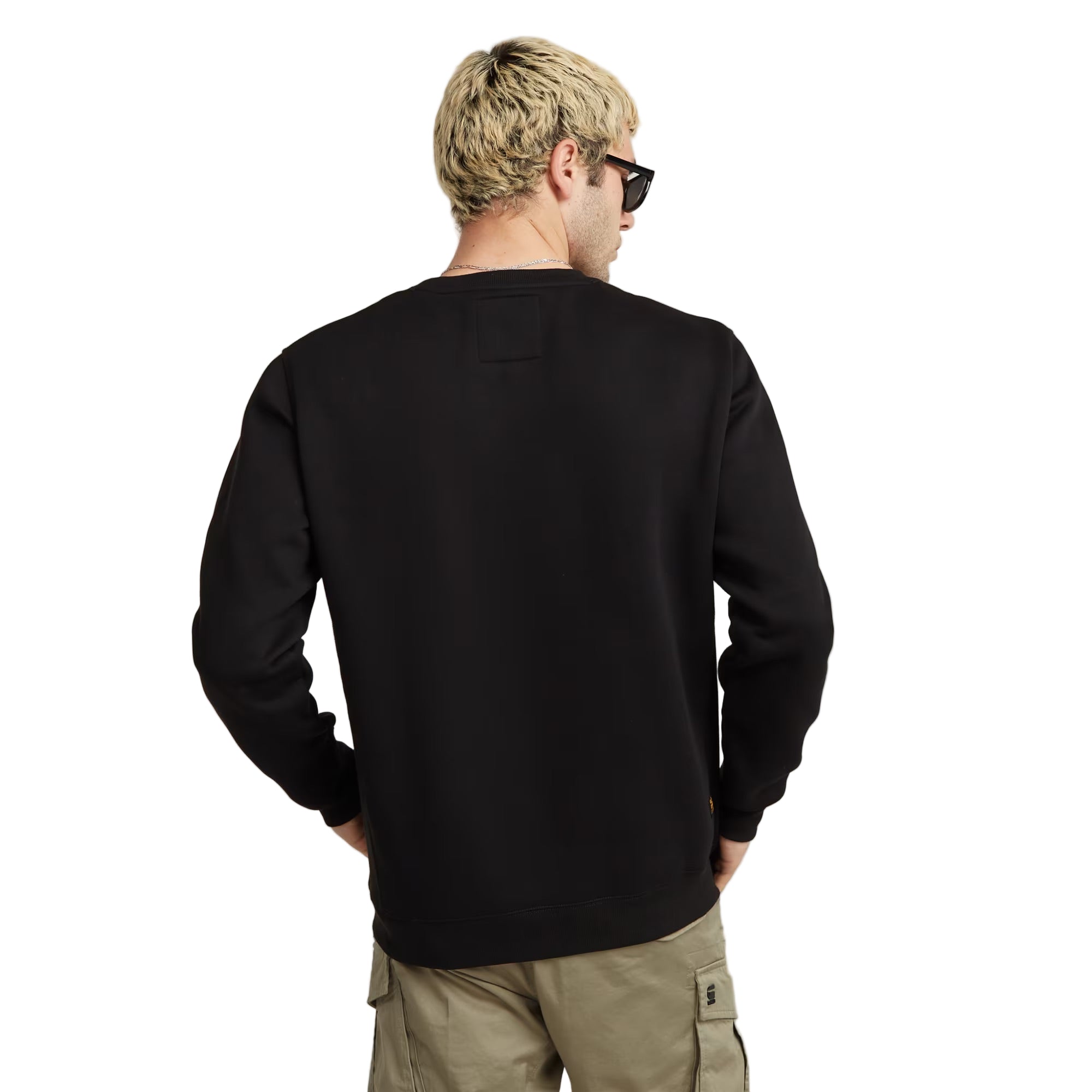 Man wearing a black sweatshirt and sunglasses from behind on a plain background