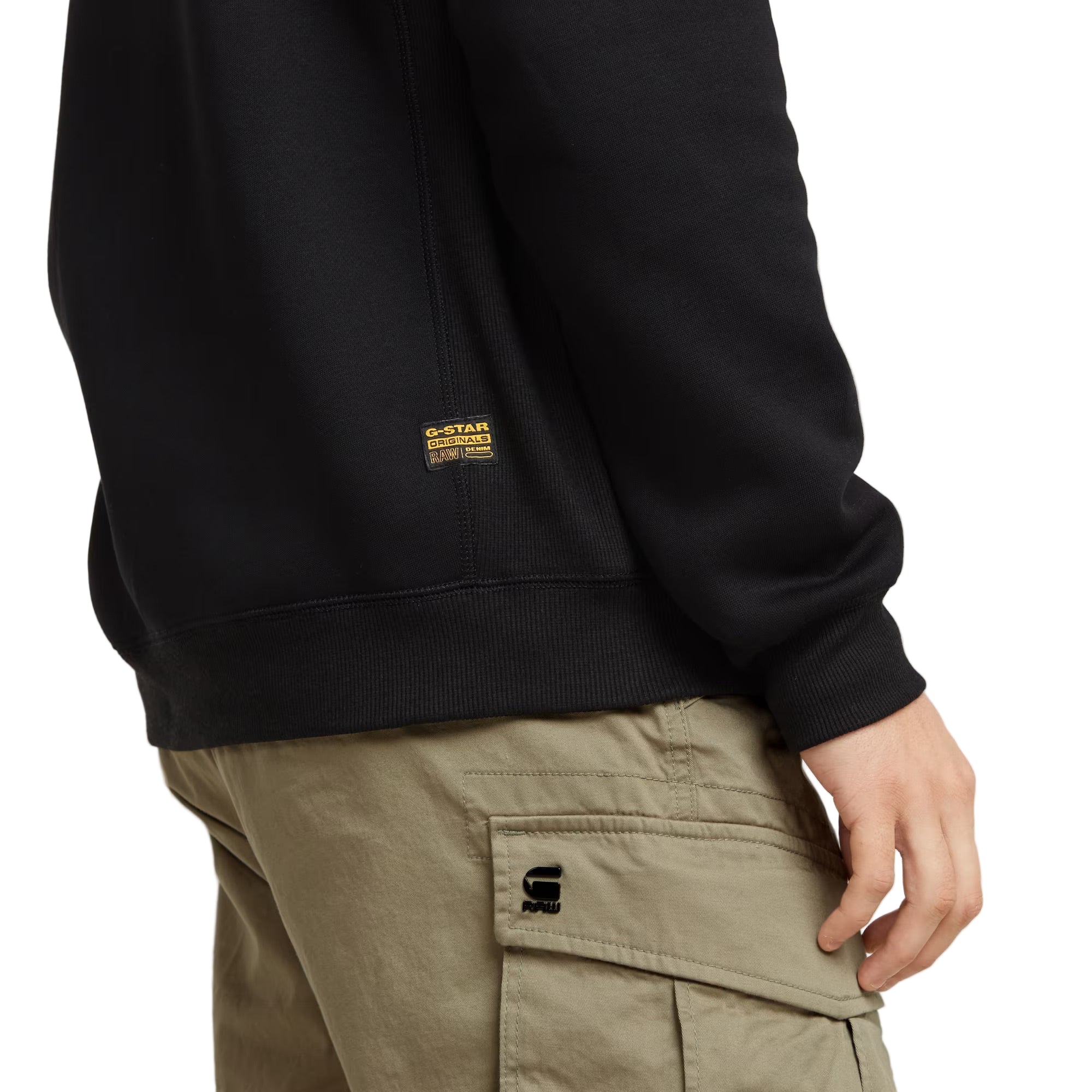 Person wearing a black sweatshirt with a brand logo on a light gray background