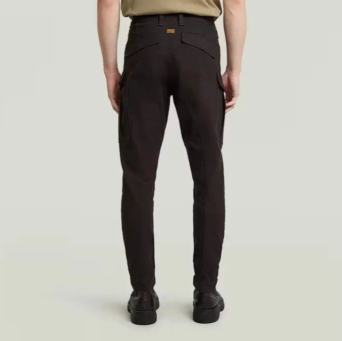 Person wearing dark brown pants on a light beige background