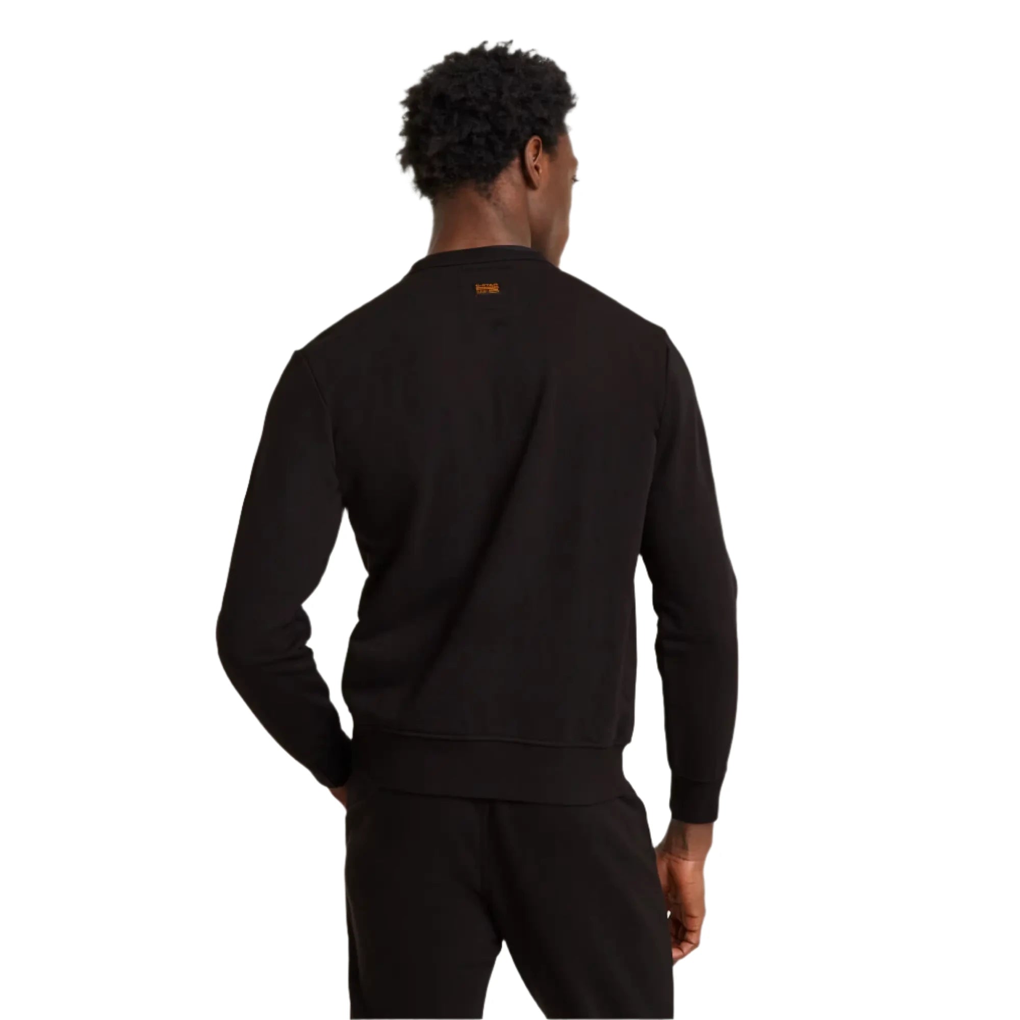 Person wearing a black tracksuit against a plain background