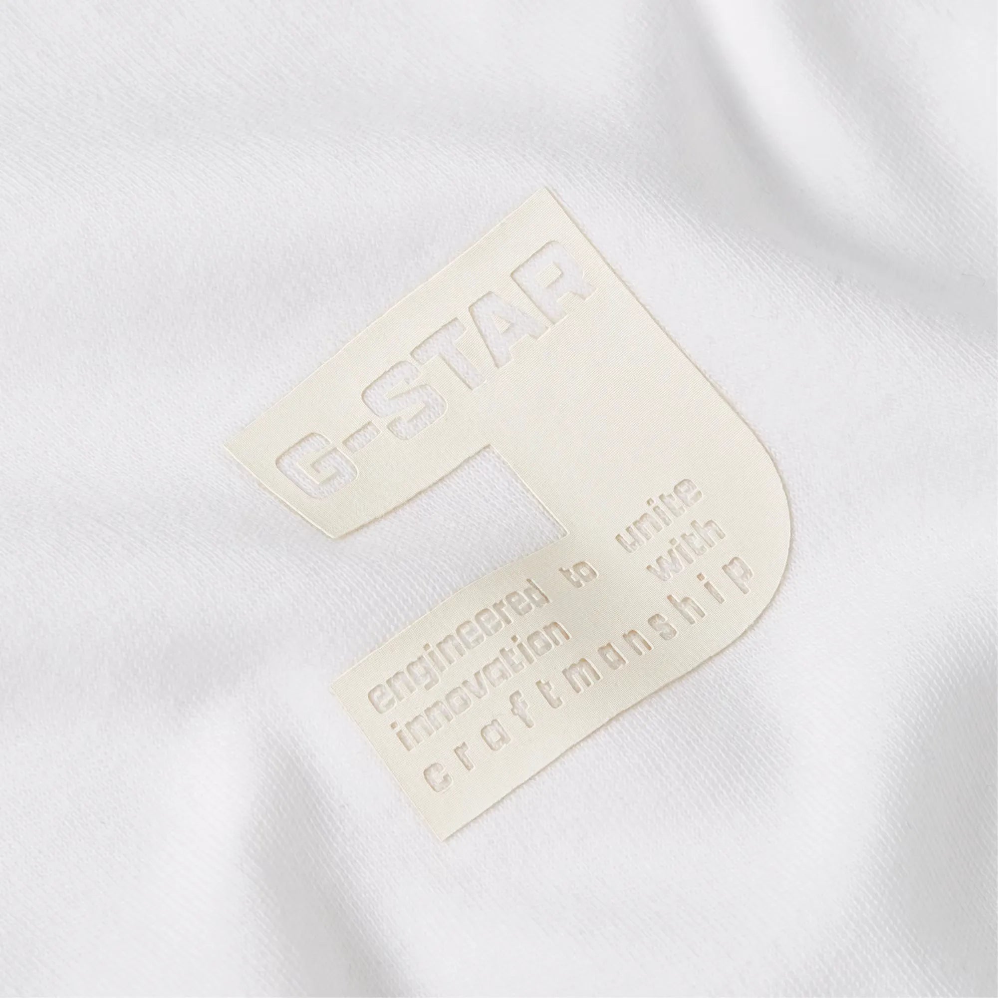 Close-up of a white shirt with a beige label featuring the brand name 'G-Star'.