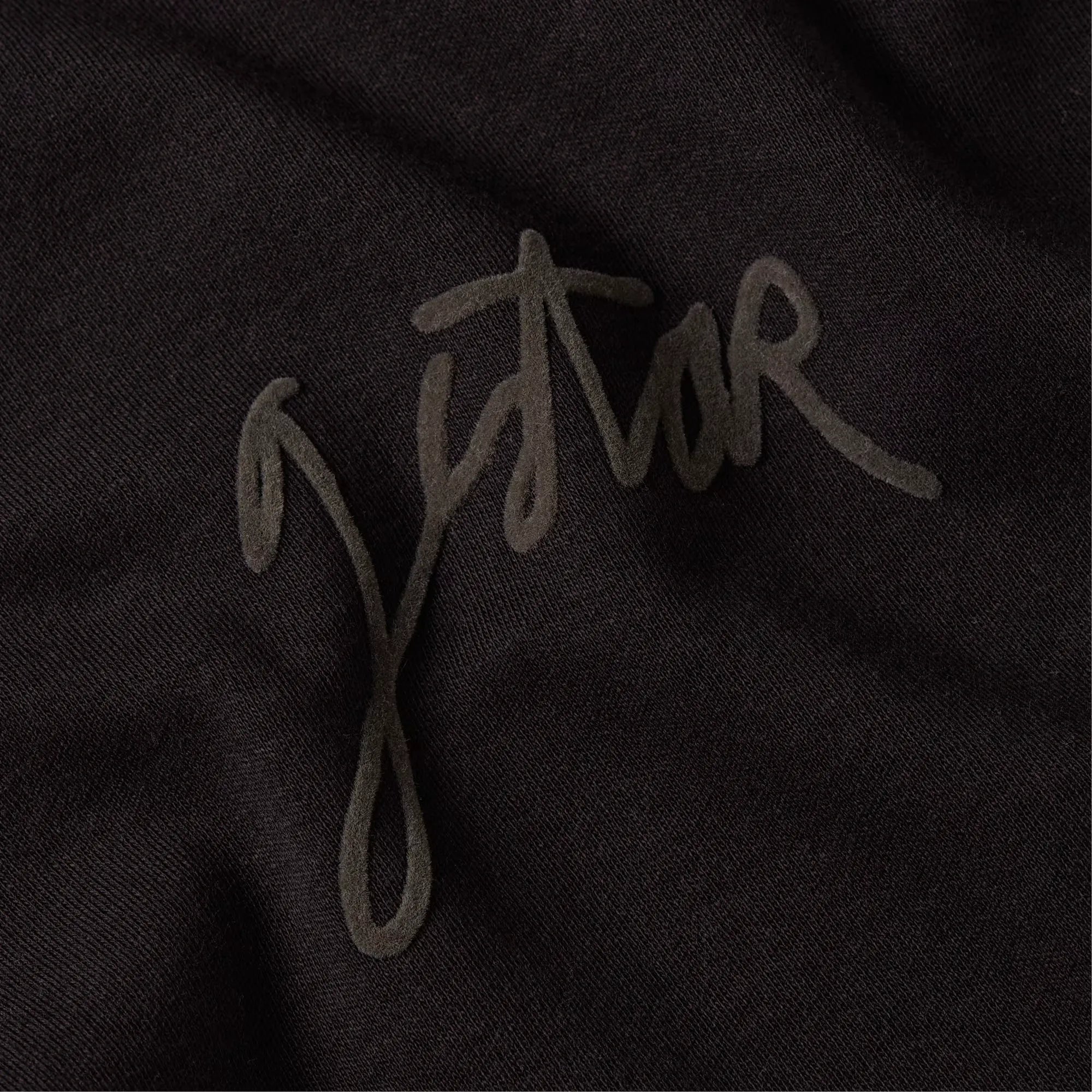 Close-up of a brand logo on a black fabric background