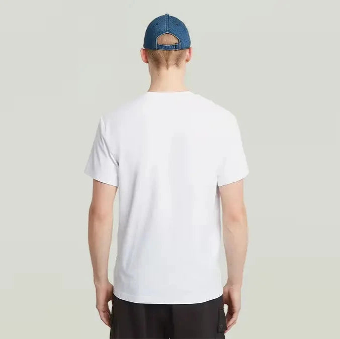 Person wearing a white t-shirt and dark pants on a plain background