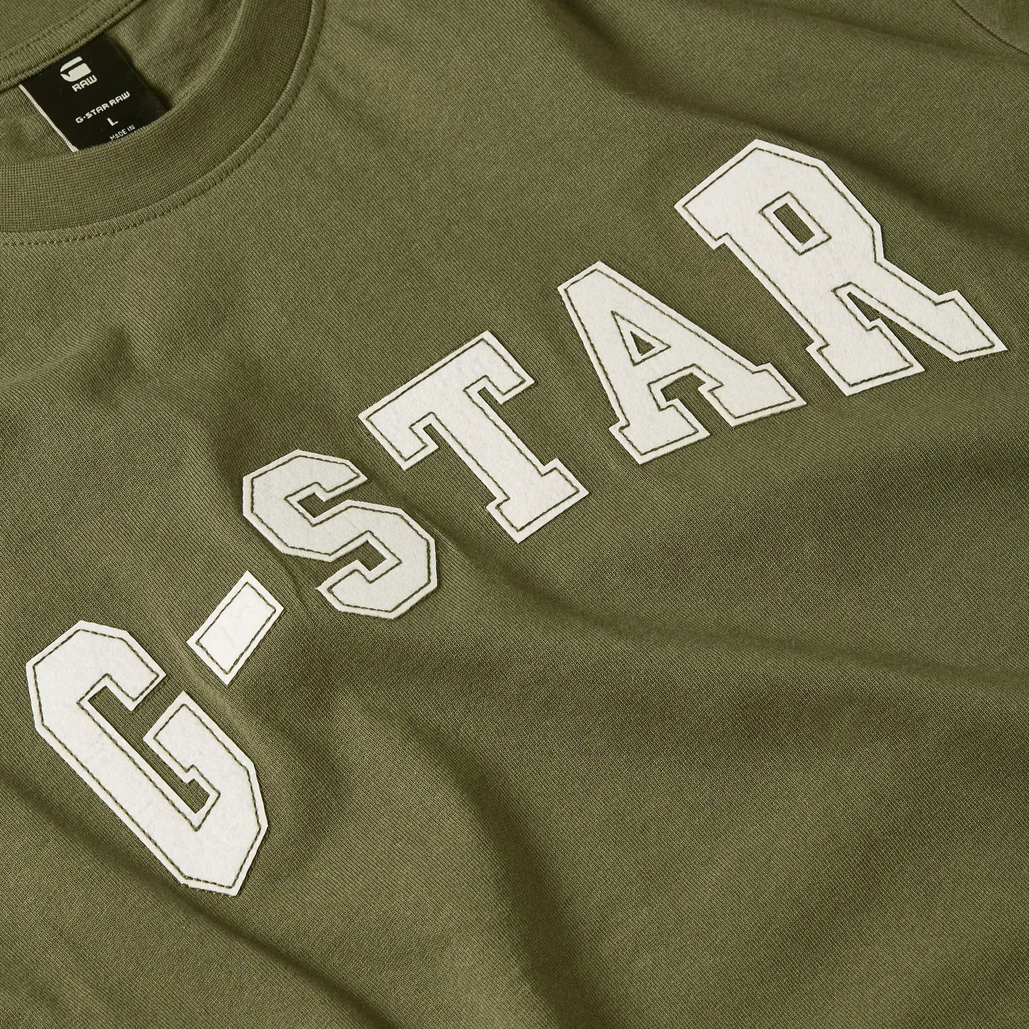 Green G-Star sweatshirt with white text on a close-up view