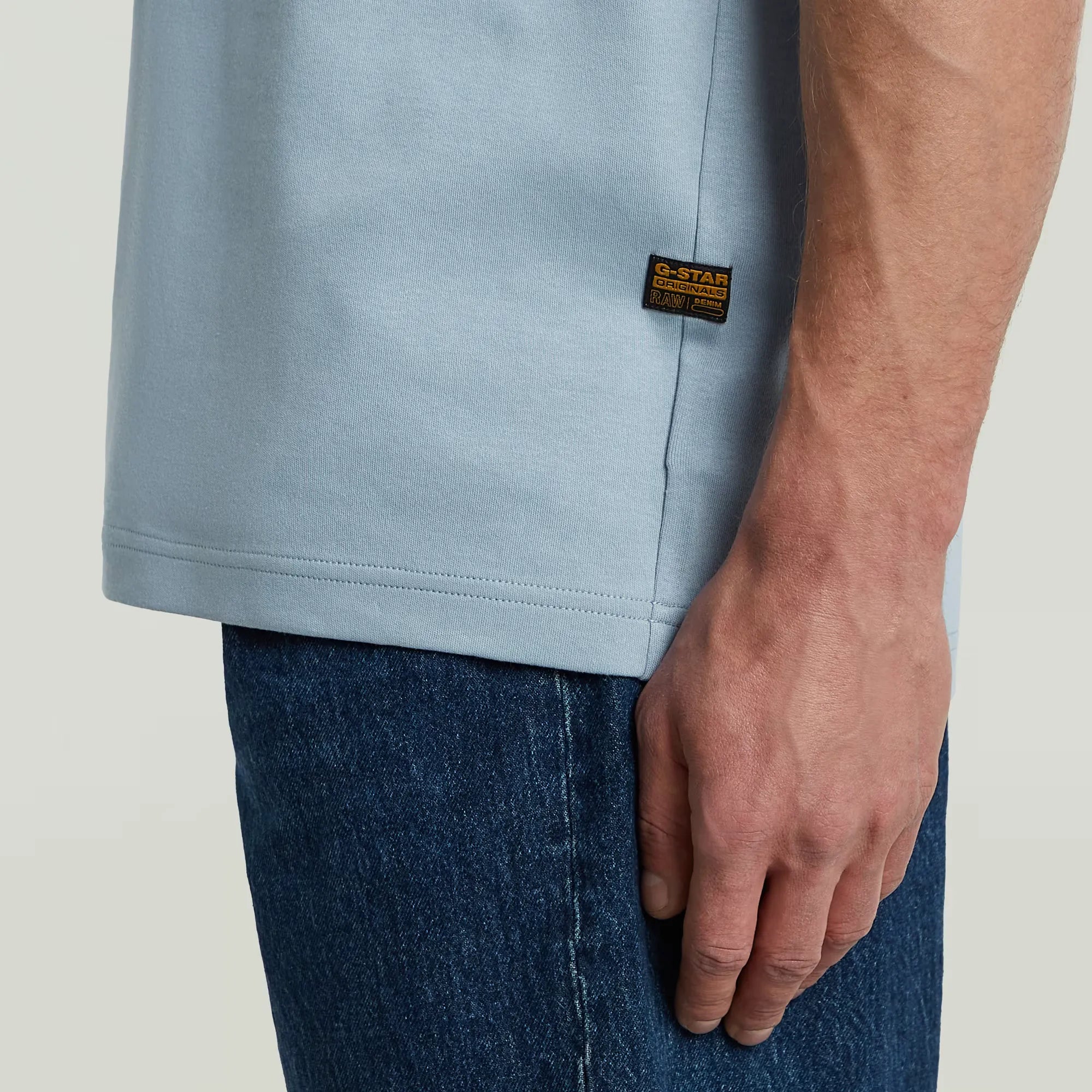 Light blue t-shirt with a brand label on a plain background