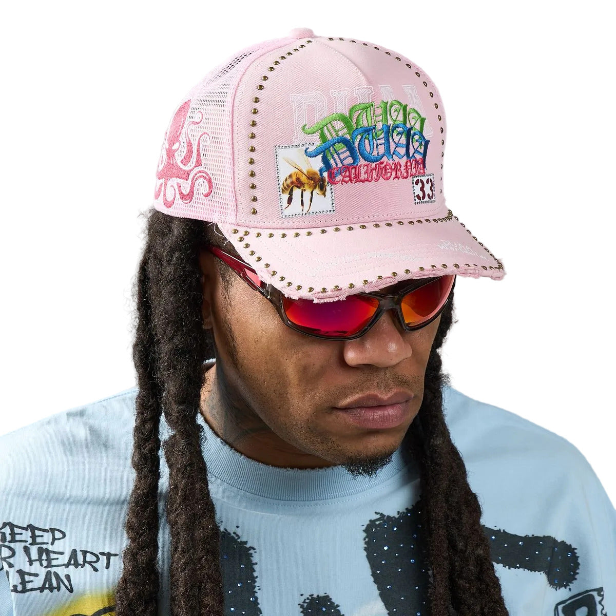 DUAA Air Hat featuring pink front panel, mesh back, multicolor graffiti embroidery, bee and 33 patch details, gold stud trim, and distressed brim snapback design.