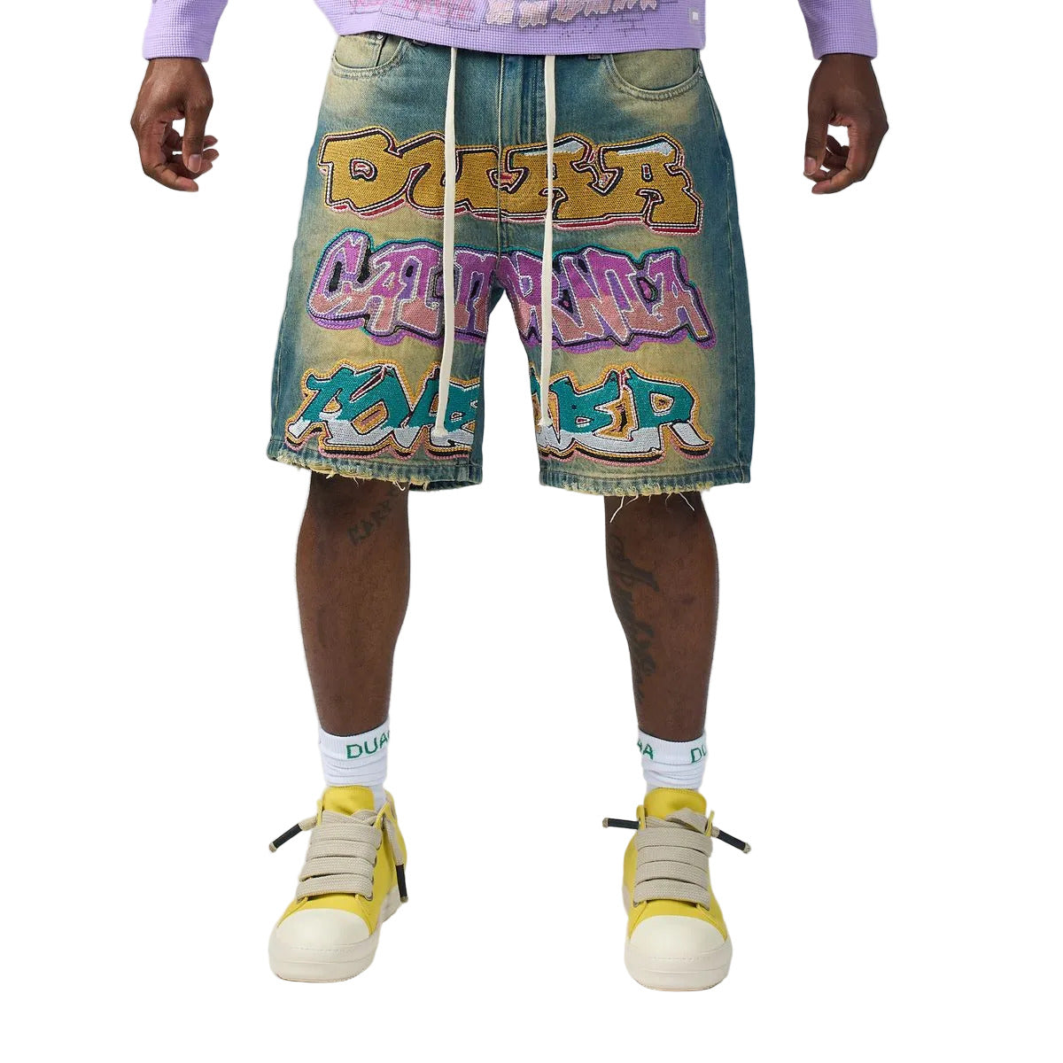 DUAA Wall Blue denim shorts in a vintage blue wash with a yellow tint, featuring a large rhinestone graffiti DUAA design, embroidered back pockets, a raw cutoff hem, and a drawstring waist.
