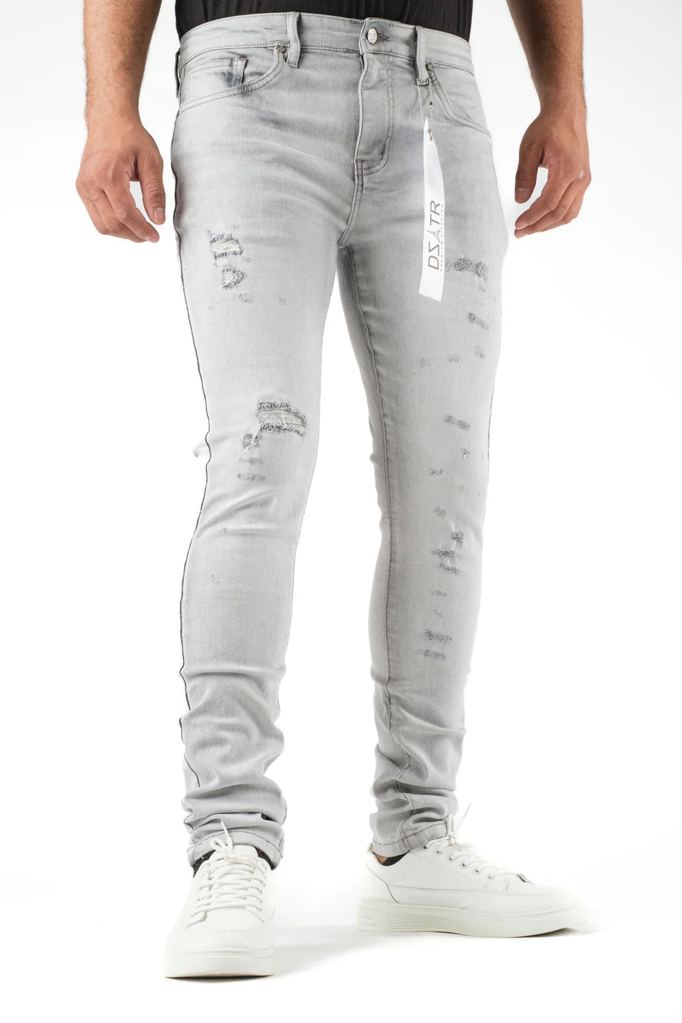 Person wearing light gray distressed jeans with a brand label on a white background