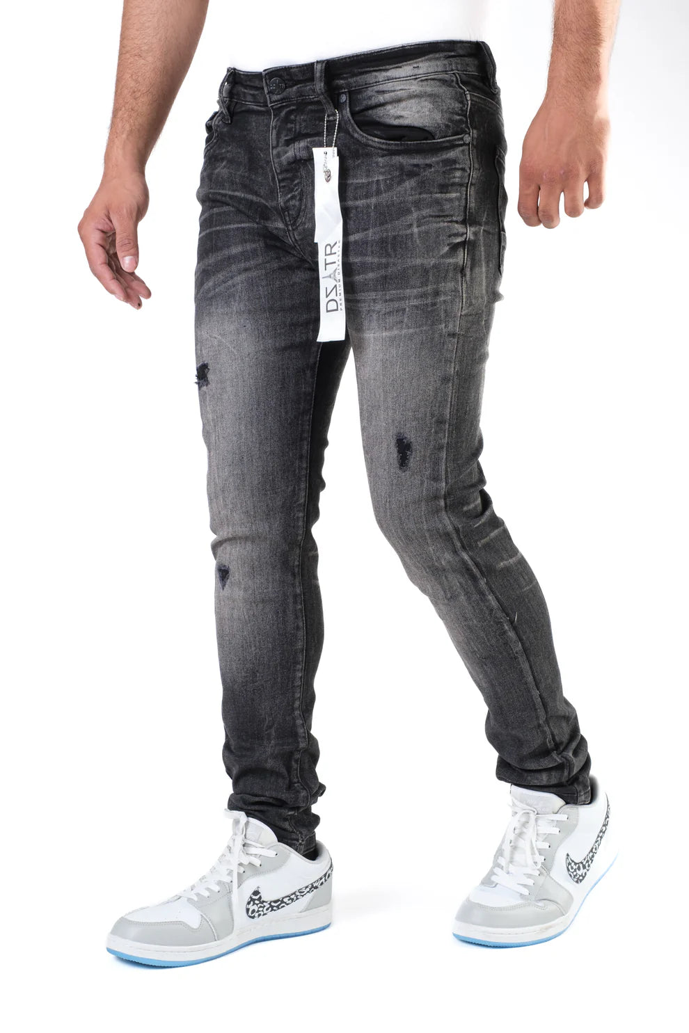 Person wearing black distressed jeans with a visible brand tag, standing against a white background.