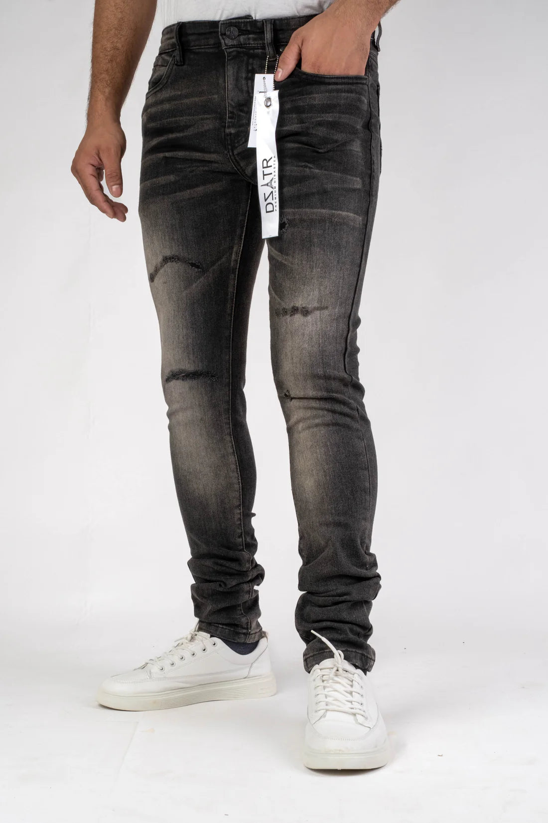 Person wearing black distressed jeans with a visible brand tag on a white background