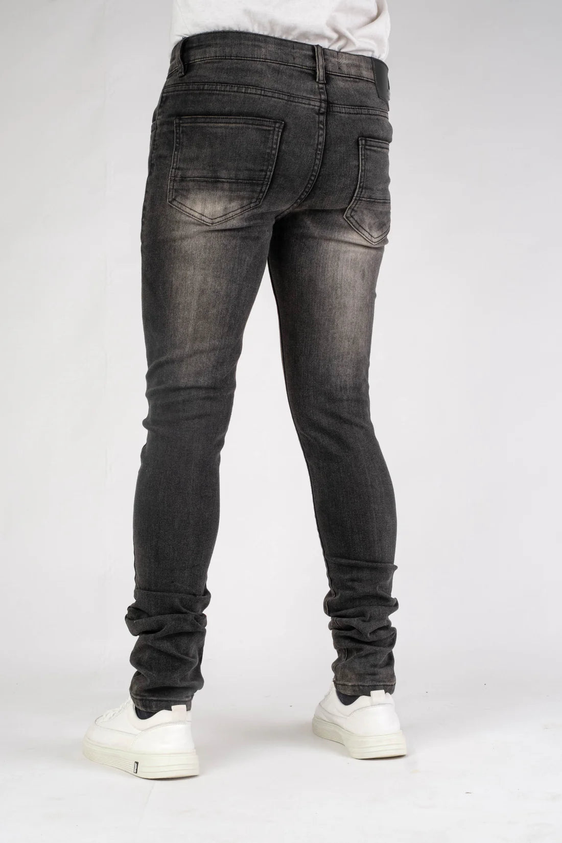 Person wearing black jeans and white sneakers on a plain background