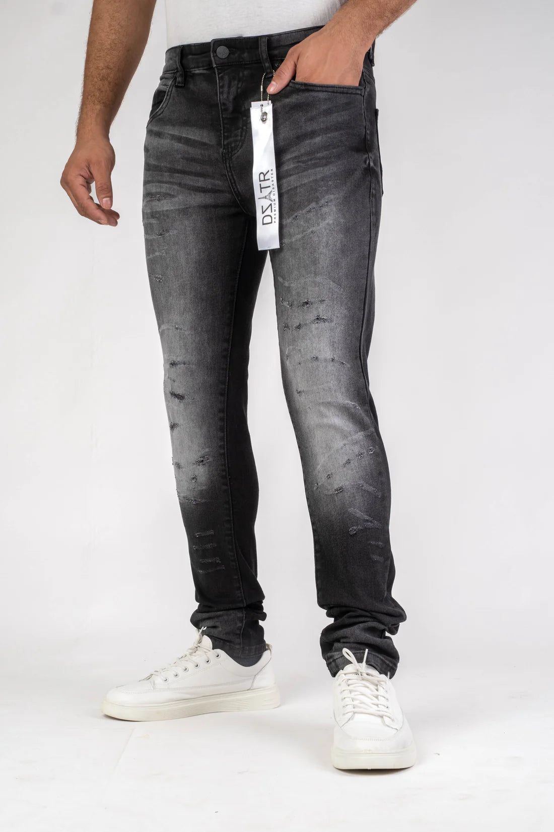 Person wearing black distressed jeans with a visible brand tag on a white background