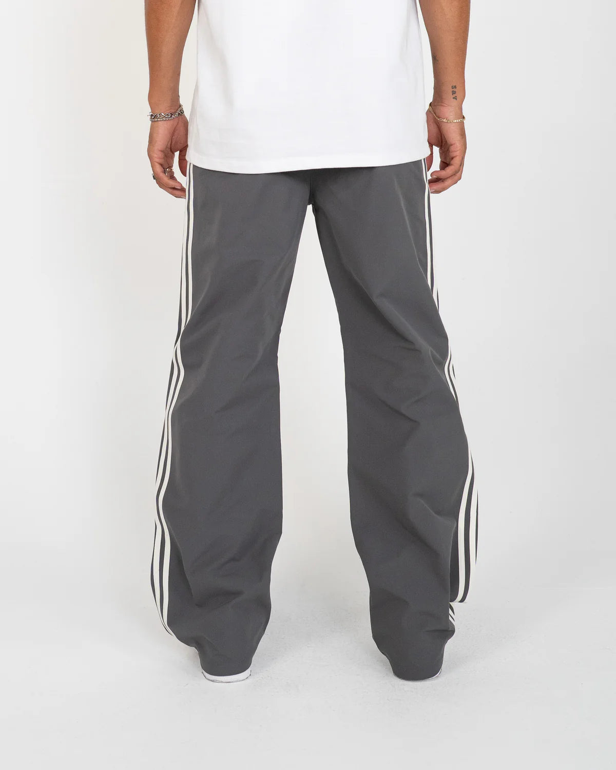 The Fogami Pants elevate everyday fashion basics with a relaxed flare silhouette, featuring bold side stripes that fold into front knee pleats for a subtle yet distinctive detail. Crafted from 100% polyester, they include an elastic waistband with an elongated interior drawcord for adjustable comfort. Additional features include side and back pockets and an embroidered logo for a polished streetwear finish.