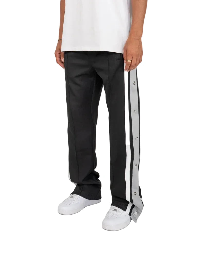 EPTM Gully Track Pants in black with side seam stripes, metal logo snap buttons, front pintucks, and relaxed flare fit