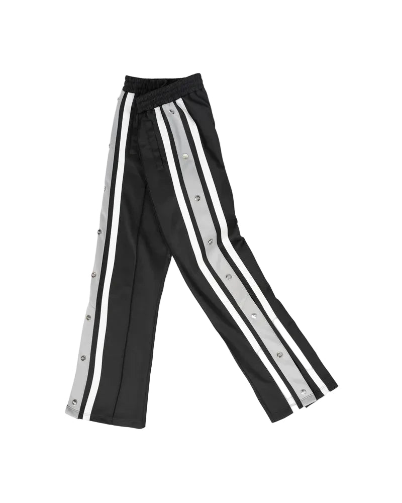 EPTM Gully Track Pants in black with side seam stripes, metal logo snap buttons, front pintucks, and relaxed flare fit