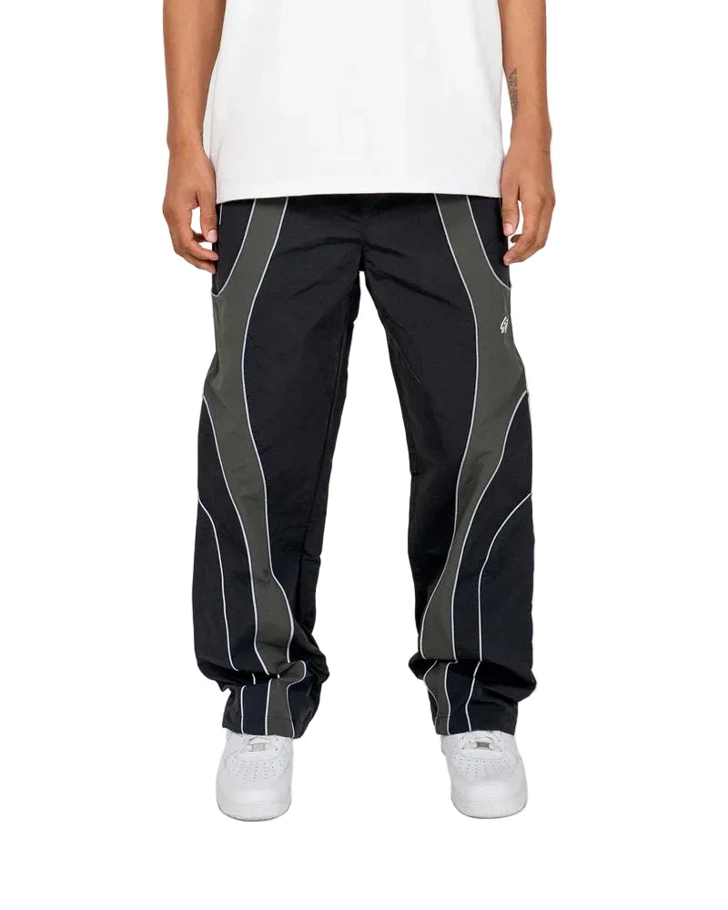 EPTM Gully Track Pants in black with side seam stripes, metal logo snap buttons, front pintucks, and relaxed flare fit