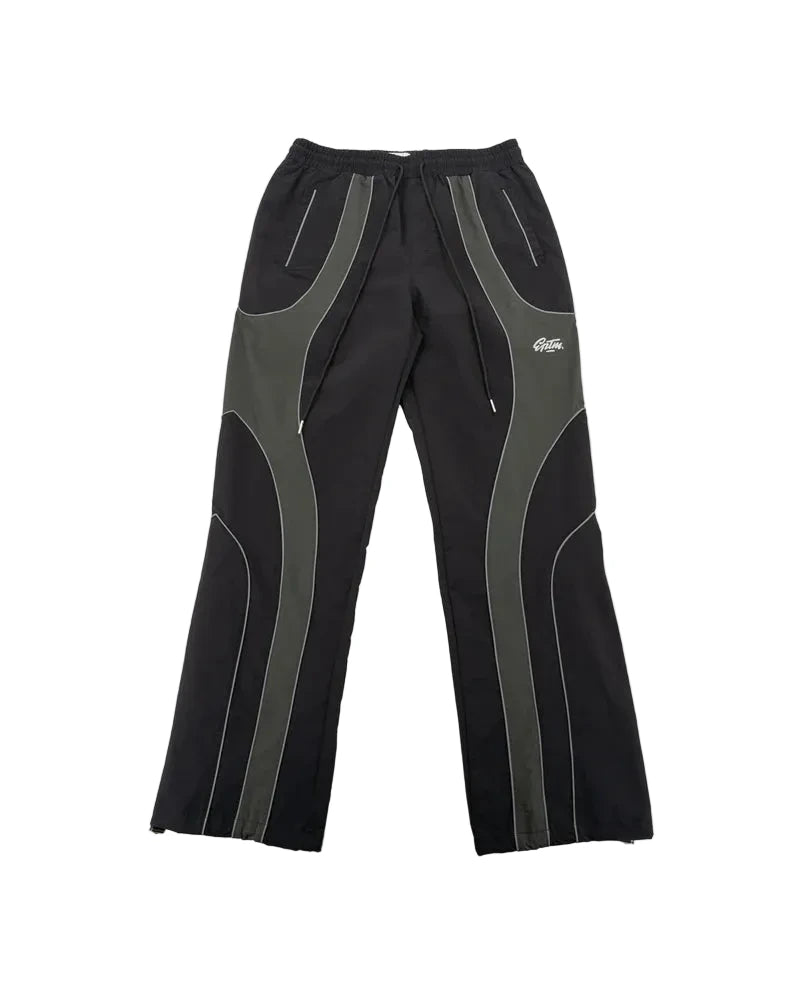 EPTM Gully Track Pants in black with side seam stripes, metal logo snap buttons, front pintucks, and relaxed flare fit