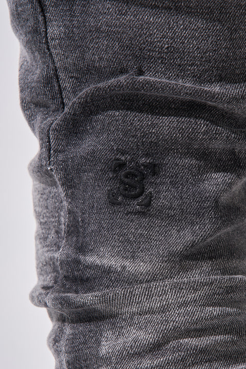 Faded black SERENEDE® FUME jeans with tapered fit, embroidered logo, and leather patch in a smoke-washed finish.