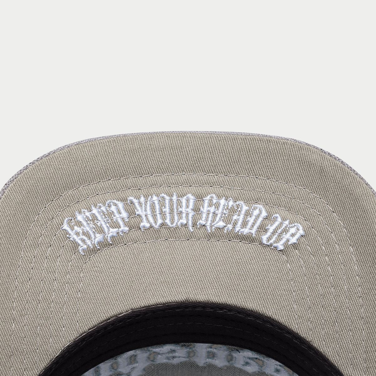 Gray cap with white embroidered text on a light gray background