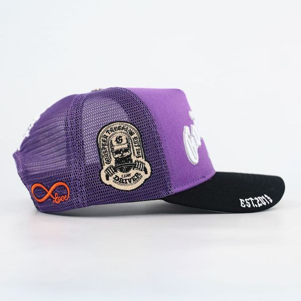Godspeed GS Forever trucker hat in purple and black featuring color-changing embroidery, mesh-back construction, collectible pin set, and limited-edition packaging.