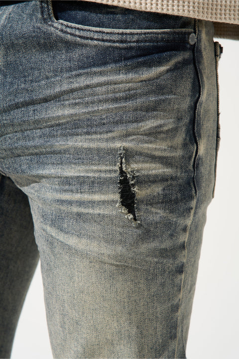 SERENEDE® Gunmetal Jeans in steel blue with grey over-dye wash, fitted construction, vintage fading, embroidered logo, and branded hardware.