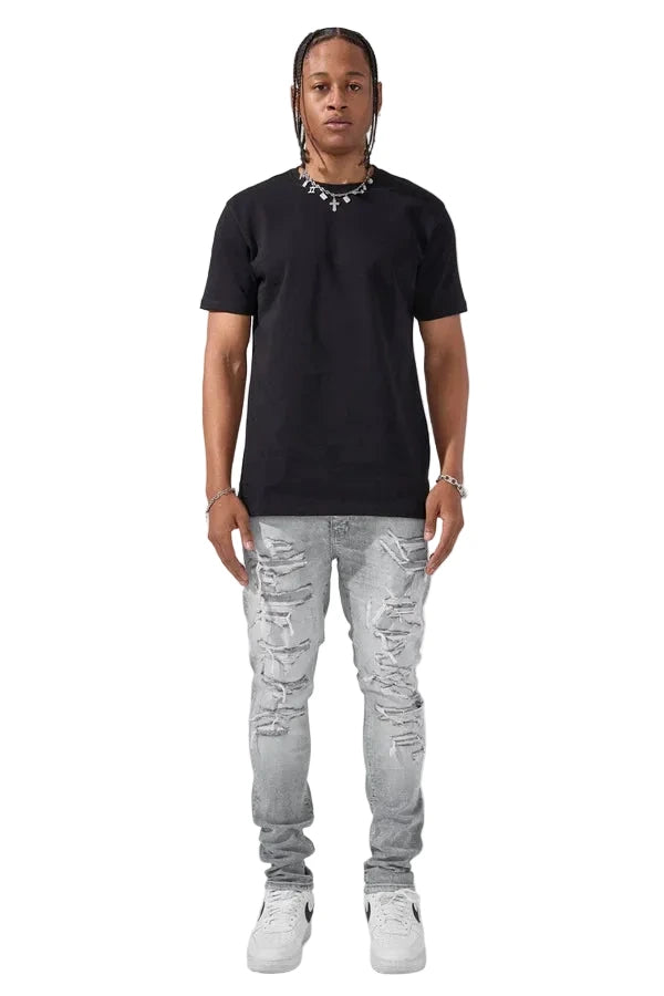 Slim taper fit denim jeans with rip-and-repair detailing and vintage-inspired distressing.