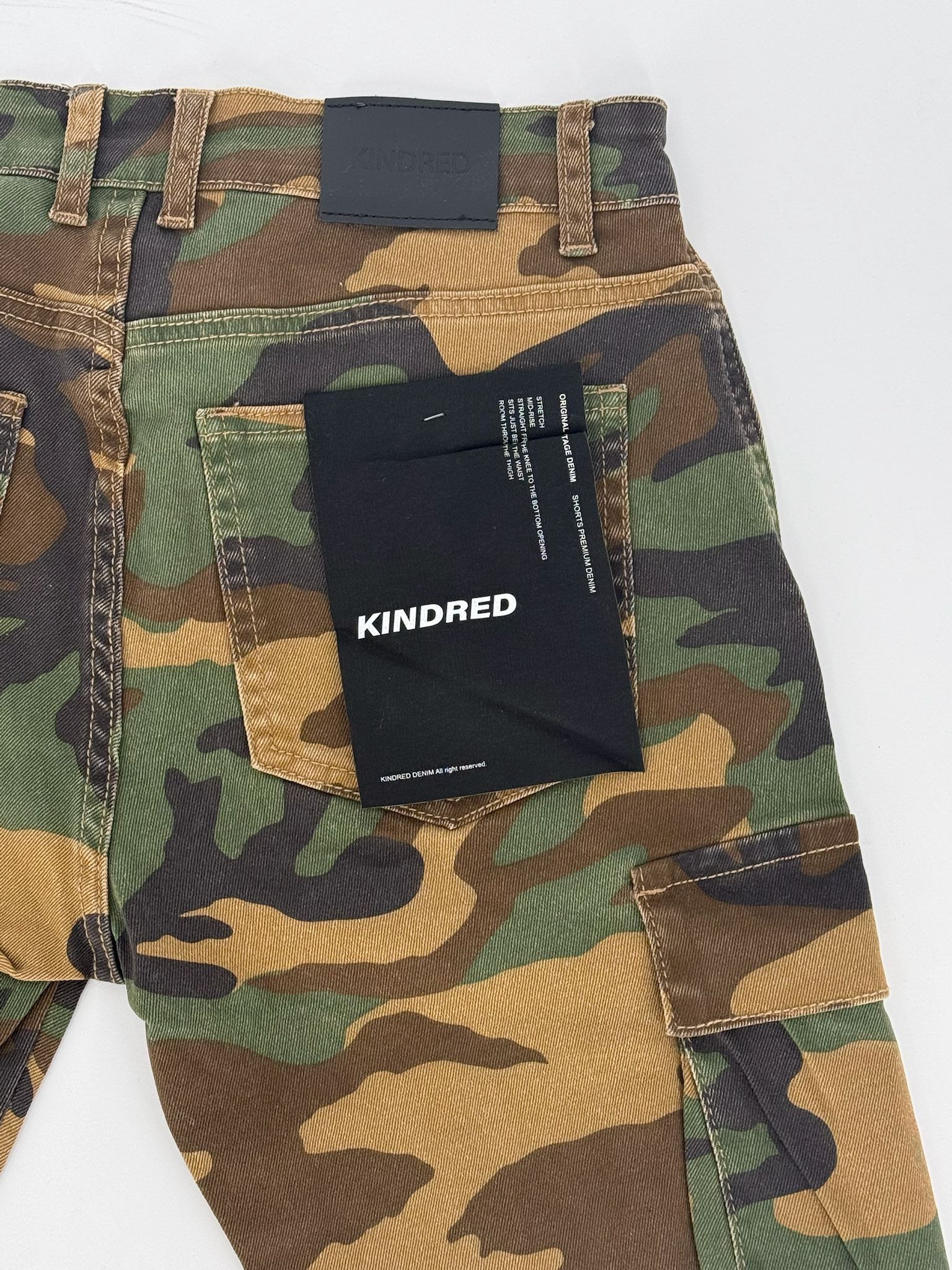 Camouflage pants with a 'Kindred' label on a white background