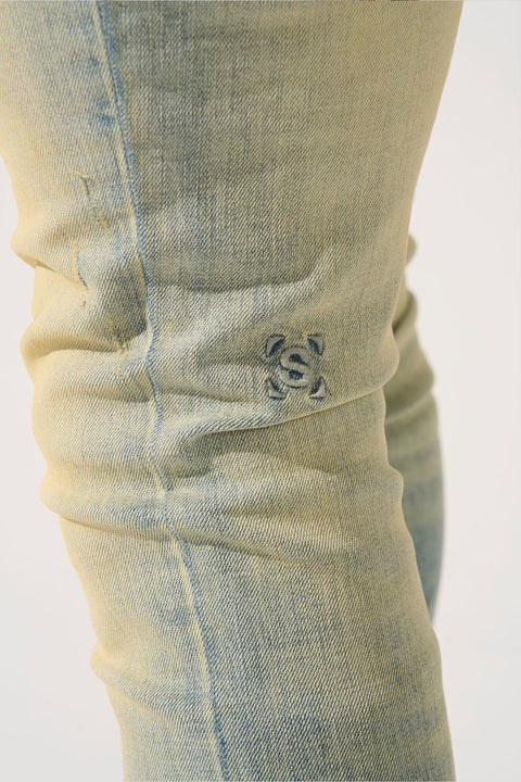SERENEDE® LIMESTONE Jeans in vintage earth yellow with fitted construction, overdyed finish, fading, and embroidered [S]® logo.