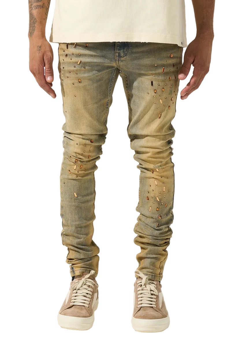 SERENEDE® Networth fitted stacked jeans in sand-washed denim with hot-fix crystal detailing, fading, and raw hem finish.
