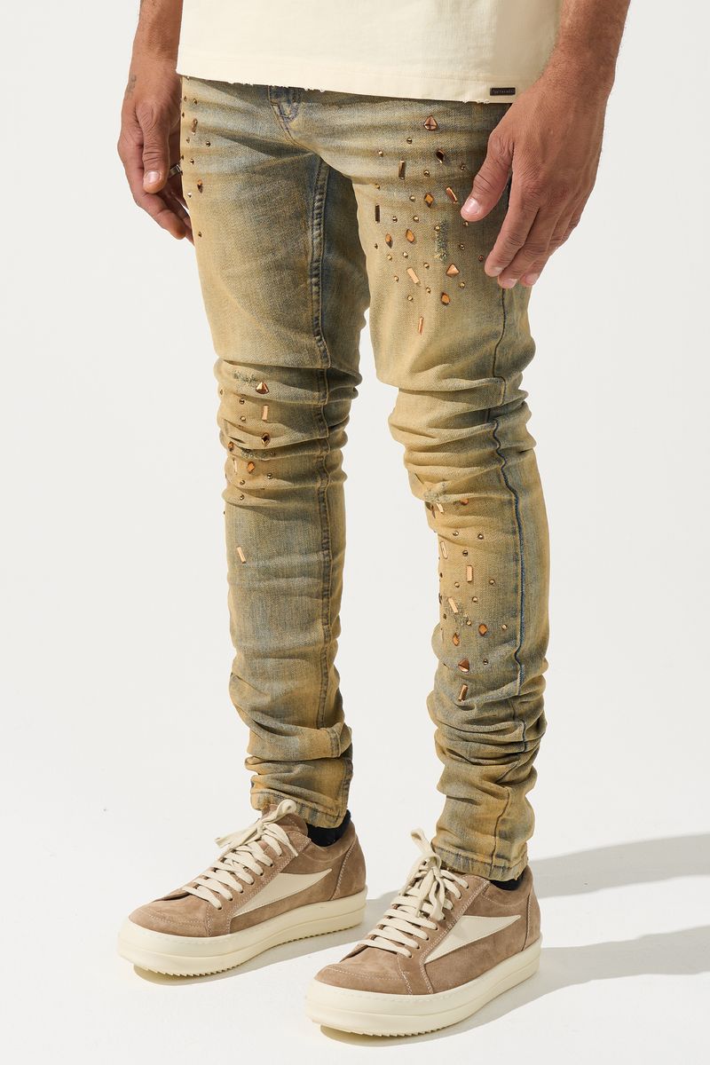 SERENEDE® Networth fitted stacked jeans in sand-washed denim with hot-fix crystal detailing, fading, and raw hem finish.