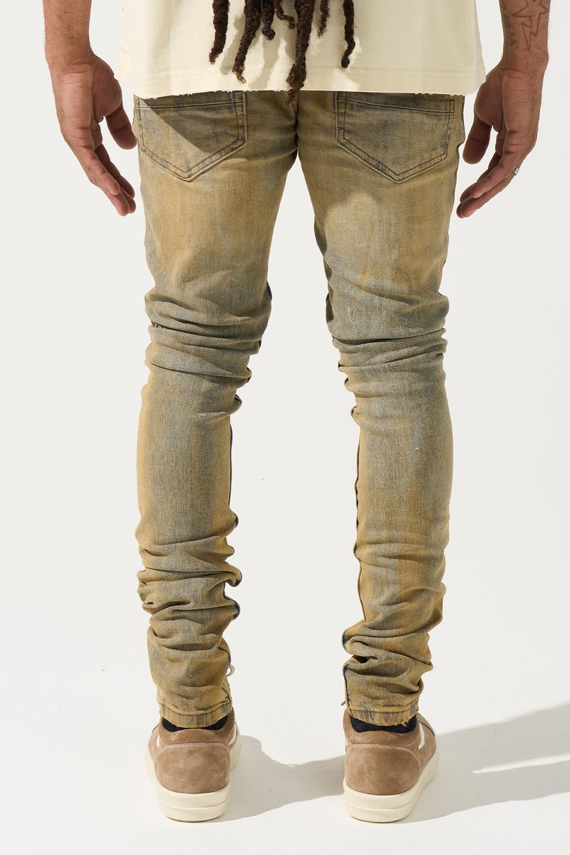 SERENEDE® Networth fitted stacked jeans in sand-washed denim with hot-fix crystal detailing, fading, and raw hem finish.
