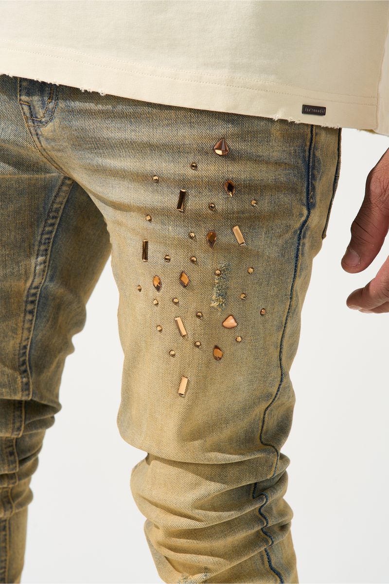 SERENEDE® Networth fitted stacked jeans in sand-washed denim with hot-fix crystal detailing, fading, and raw hem finish.