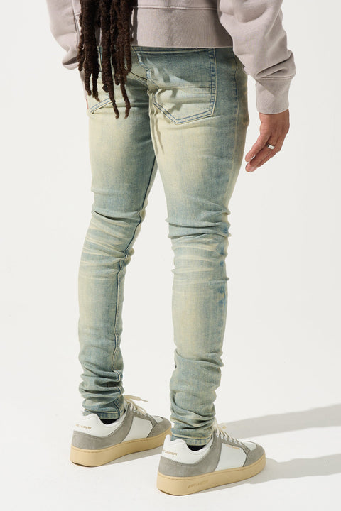 SERENEDE® Nomad Jeans in light vintage earth wash with resin wax coating, fitted construction, subtle fading, and branded hardware.