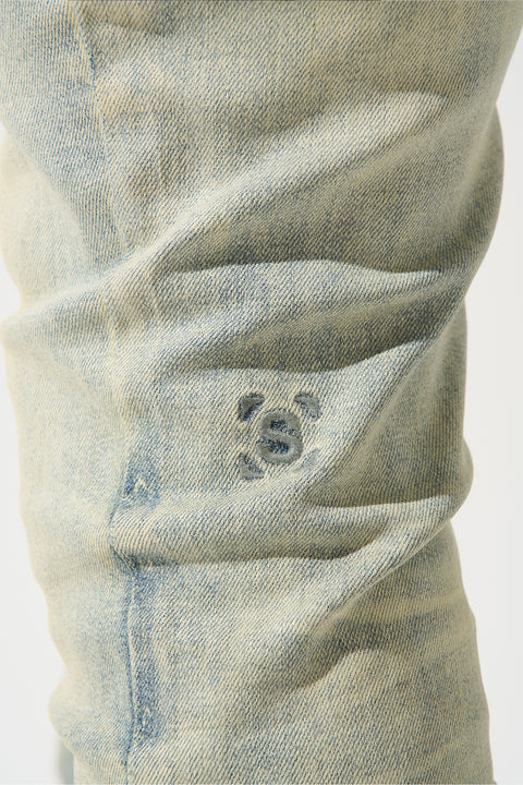 SERENEDE® Nomad Jeans in light vintage earth wash with resin wax coating, fitted construction, subtle fading, and branded hardware.