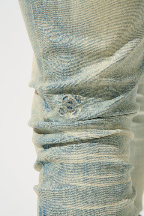 SERENEDE® Nomad Jeans in light vintage earth wash with resin wax coating, fitted construction, subtle fading, and branded hardware.