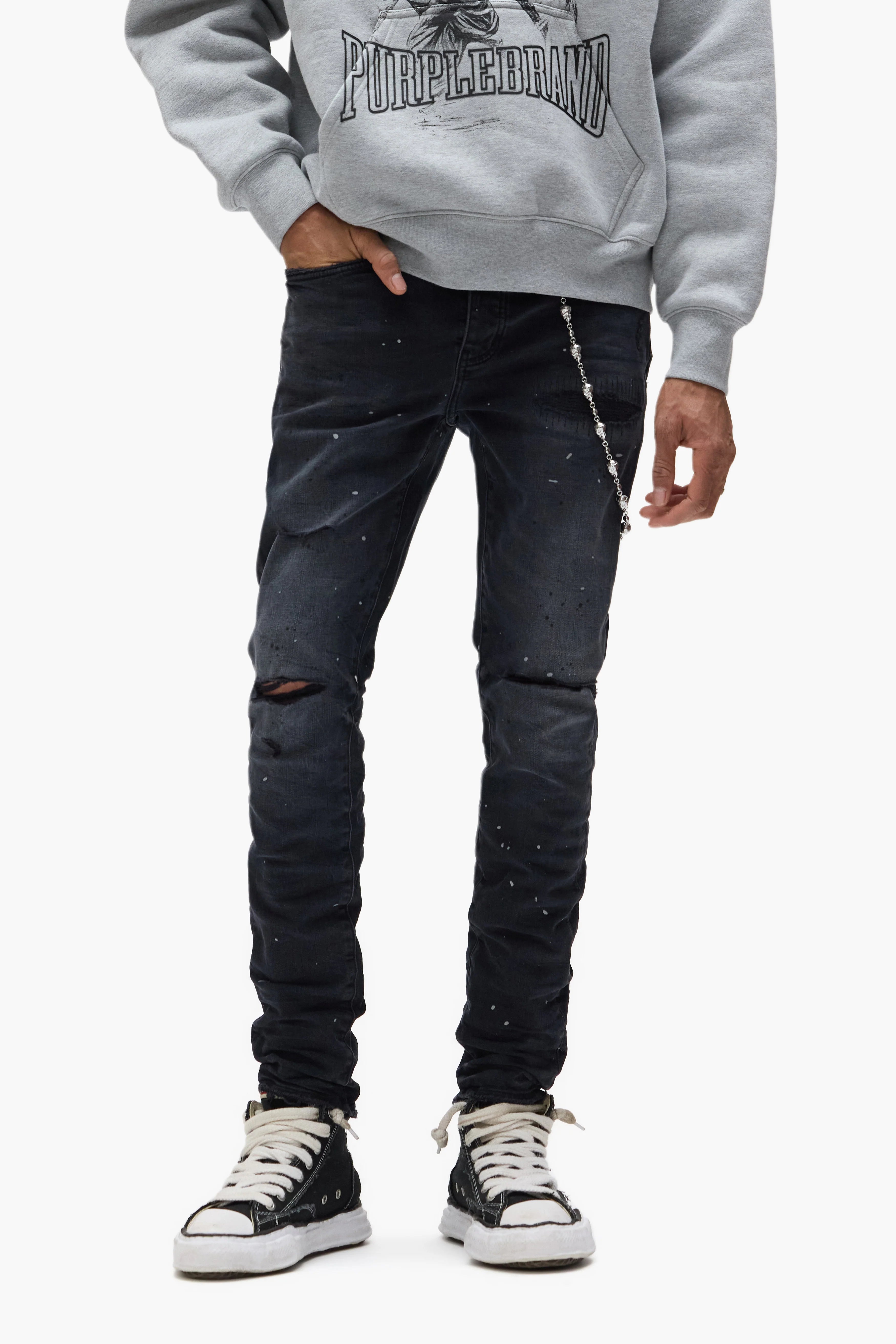 Purple Brand Core White Label black skinny jeans with distressed knees, repaired and hand-finished detailing, reflective paint accents, and branded leather patch.