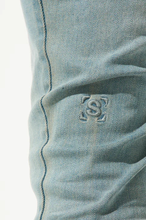 Slate blue skinny fit denim with fading, distressing, leather waistband patch, and SERENEDE® branded hardware.
