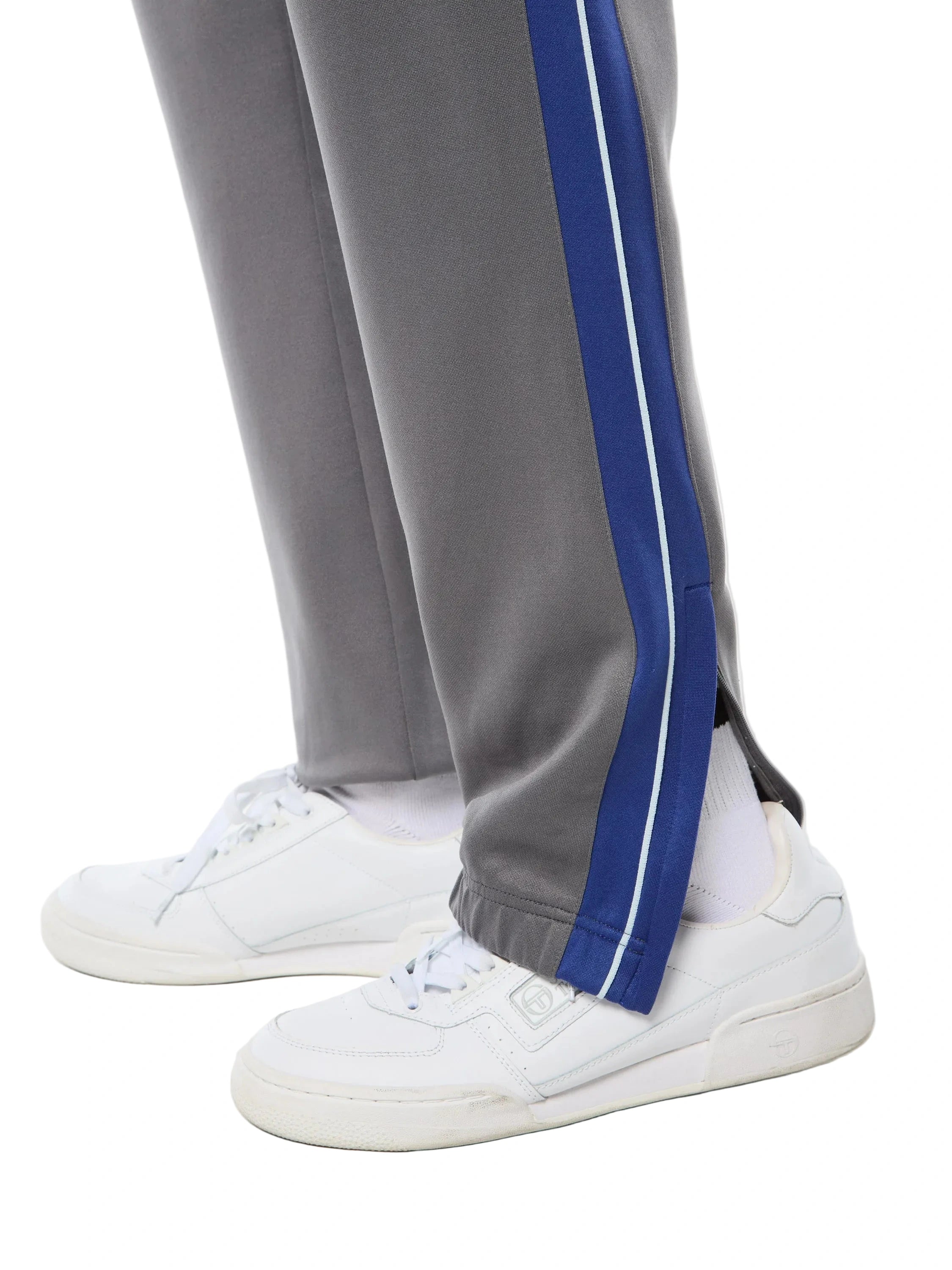 Premium track pants with elastic waistband, rear zippered welt pocket, embroidered Sergio Tacchini logo, contrast panels and piping down legs, and adjustable ankle zips